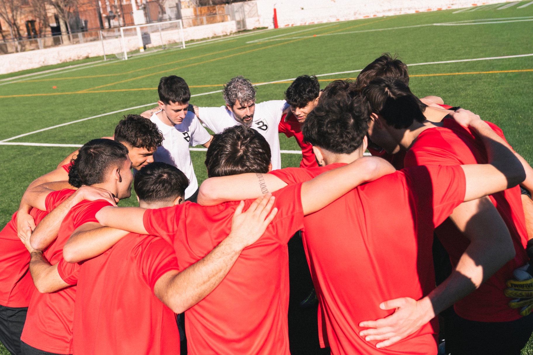Coach and players united in a team huddle on the pitch